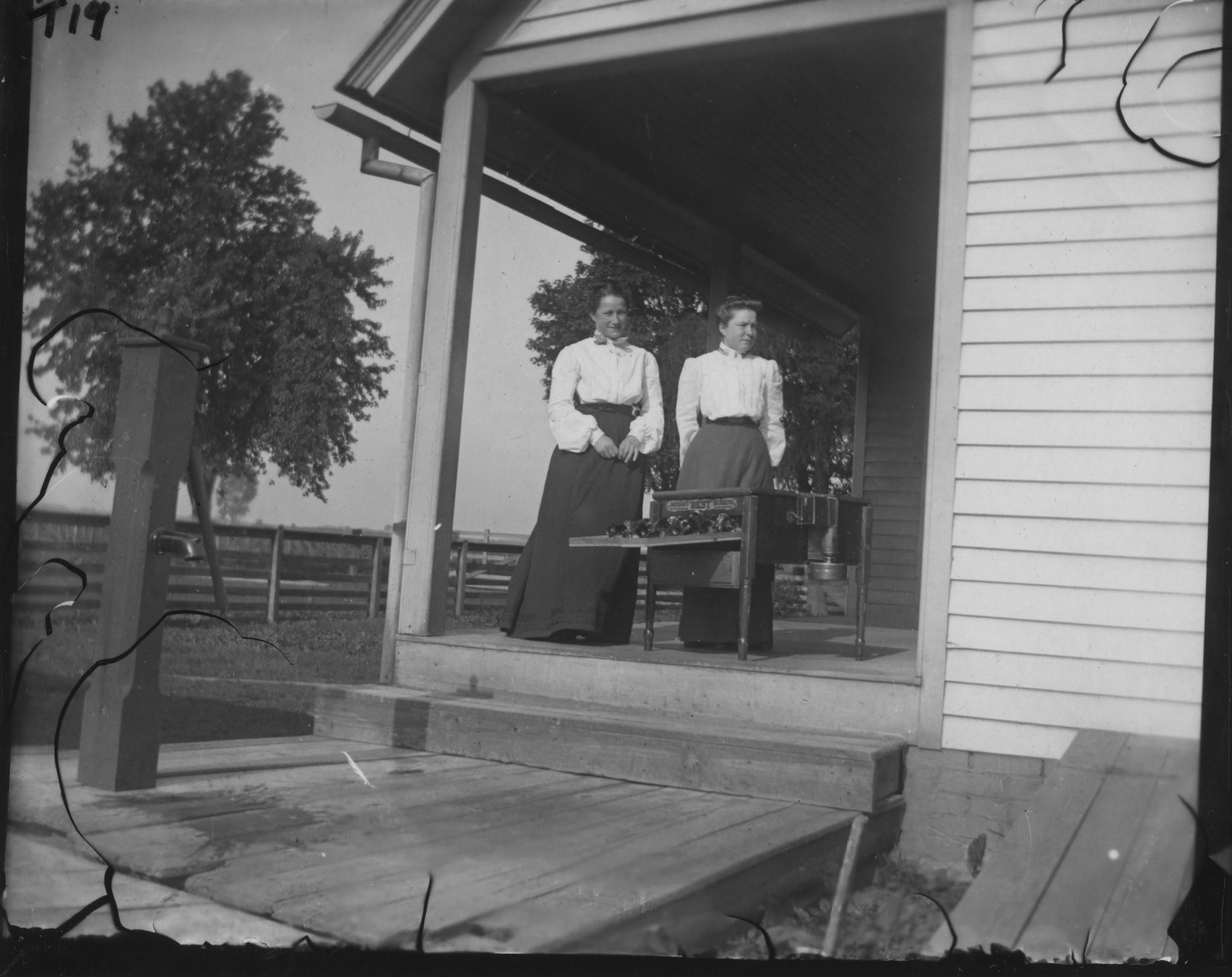 Photograph of two women standing on a porch.