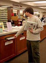 Man returning materials into the book drop at the Circulation Desk.