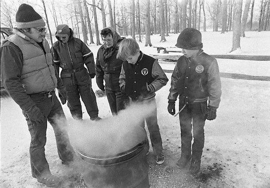 Children stand around a kettle of boiling sap 