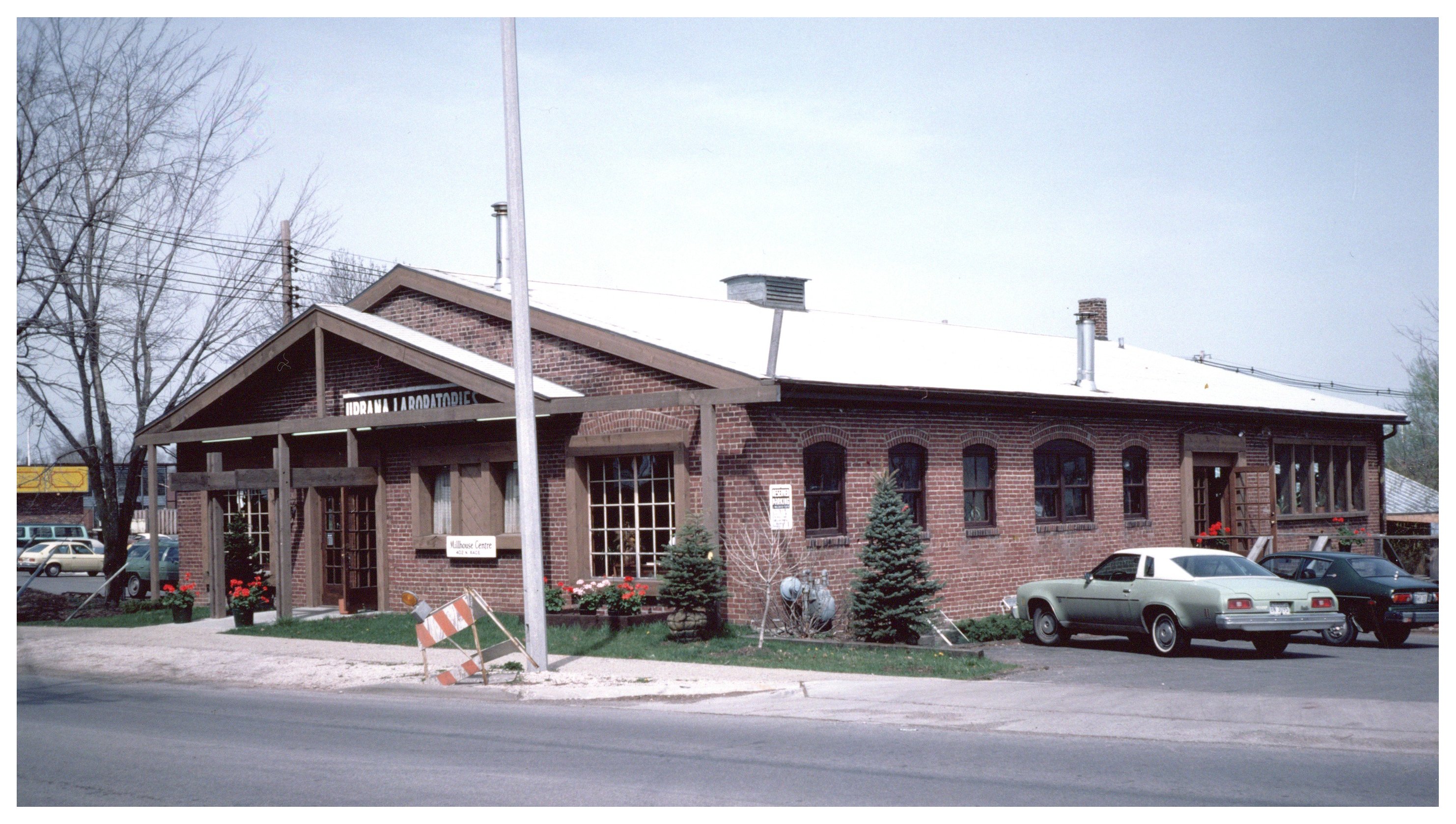 A color photograph of the brick building that now houses Silvercreek Restaurant, taken sometime between 1979 and 1989, when it was the Millhouse Centre..