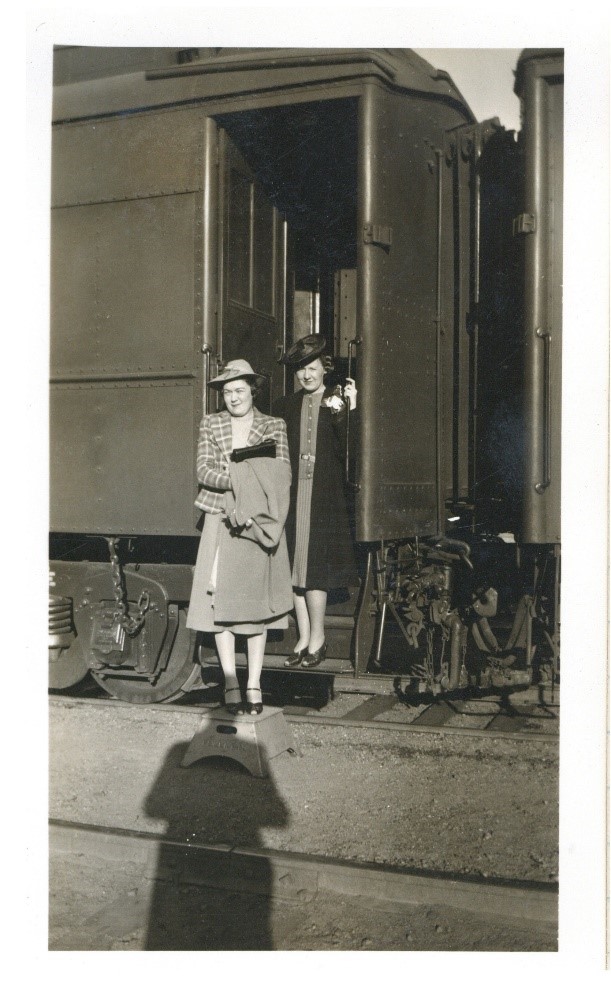 Black and white photograph of Mary Ellen and a friend standing next to a train.