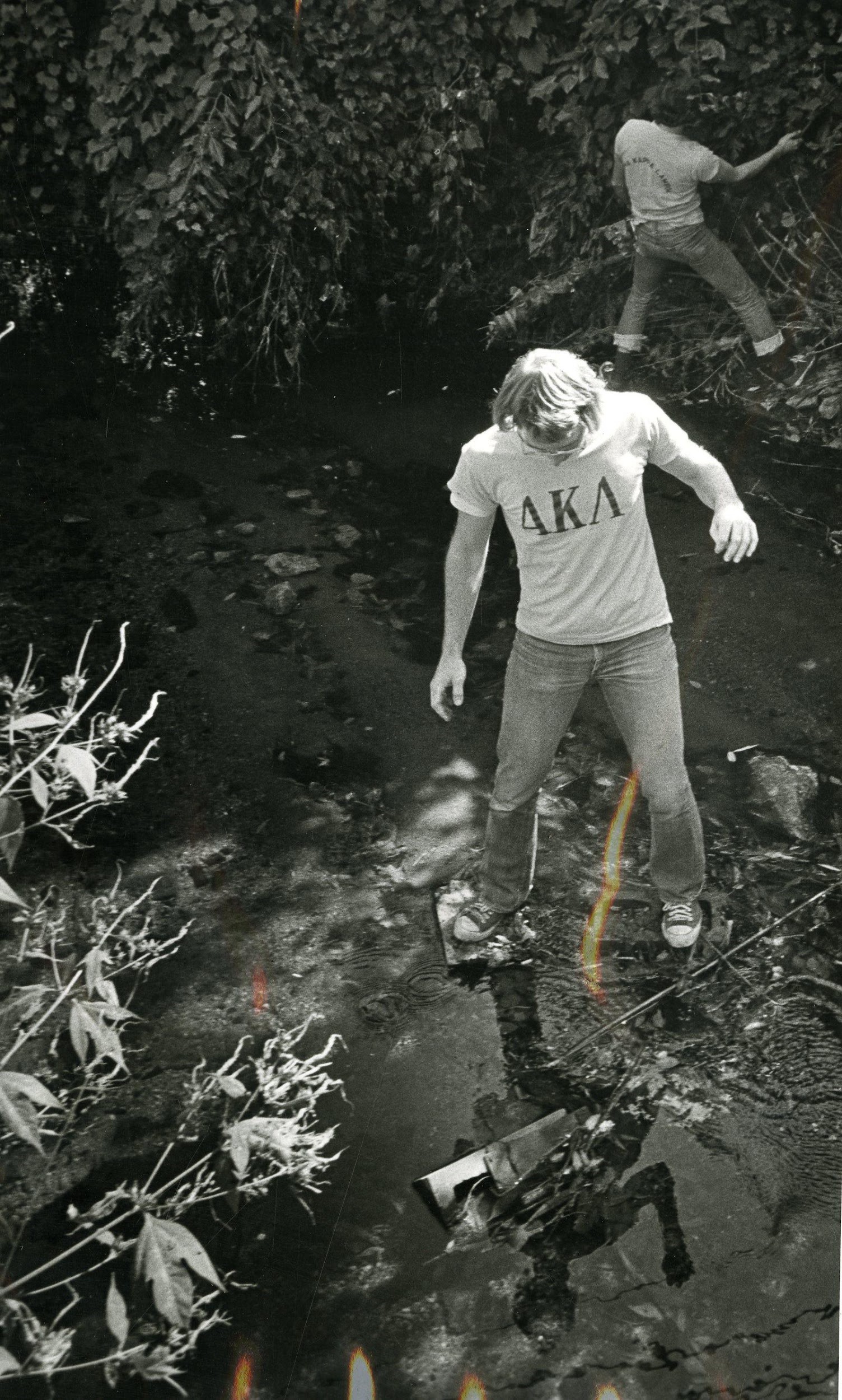 Photograph of young man walking in creek 