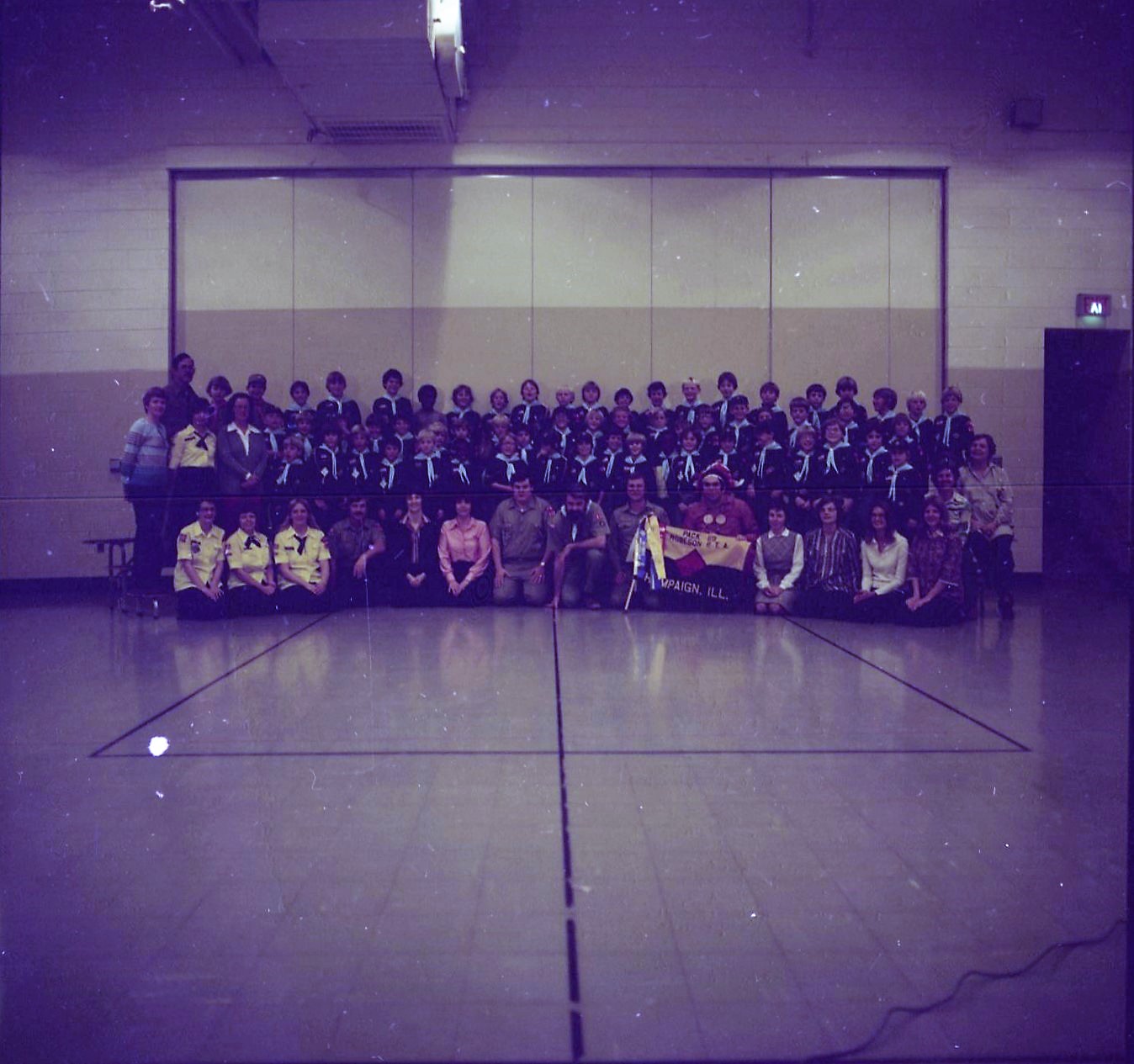 A photograph of a large group of boy scouts in a gymnasium.