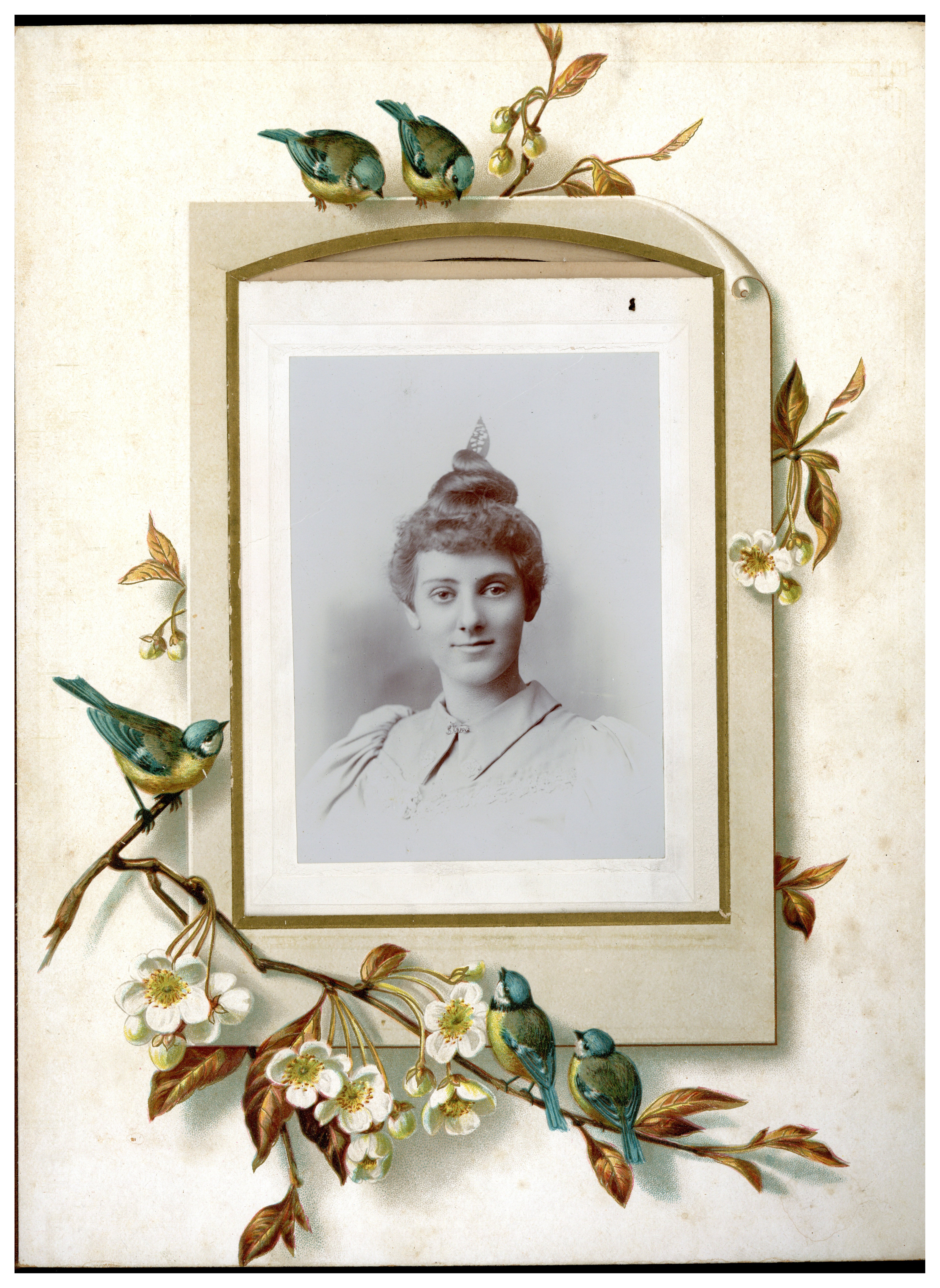 A black and white photograph from the chest of of a women with a bun on the top of her head with a decorative leaf poking out of the top. The photograph is framed by a scrapbook page with decorative plants and flower surrounding the photograph. 
