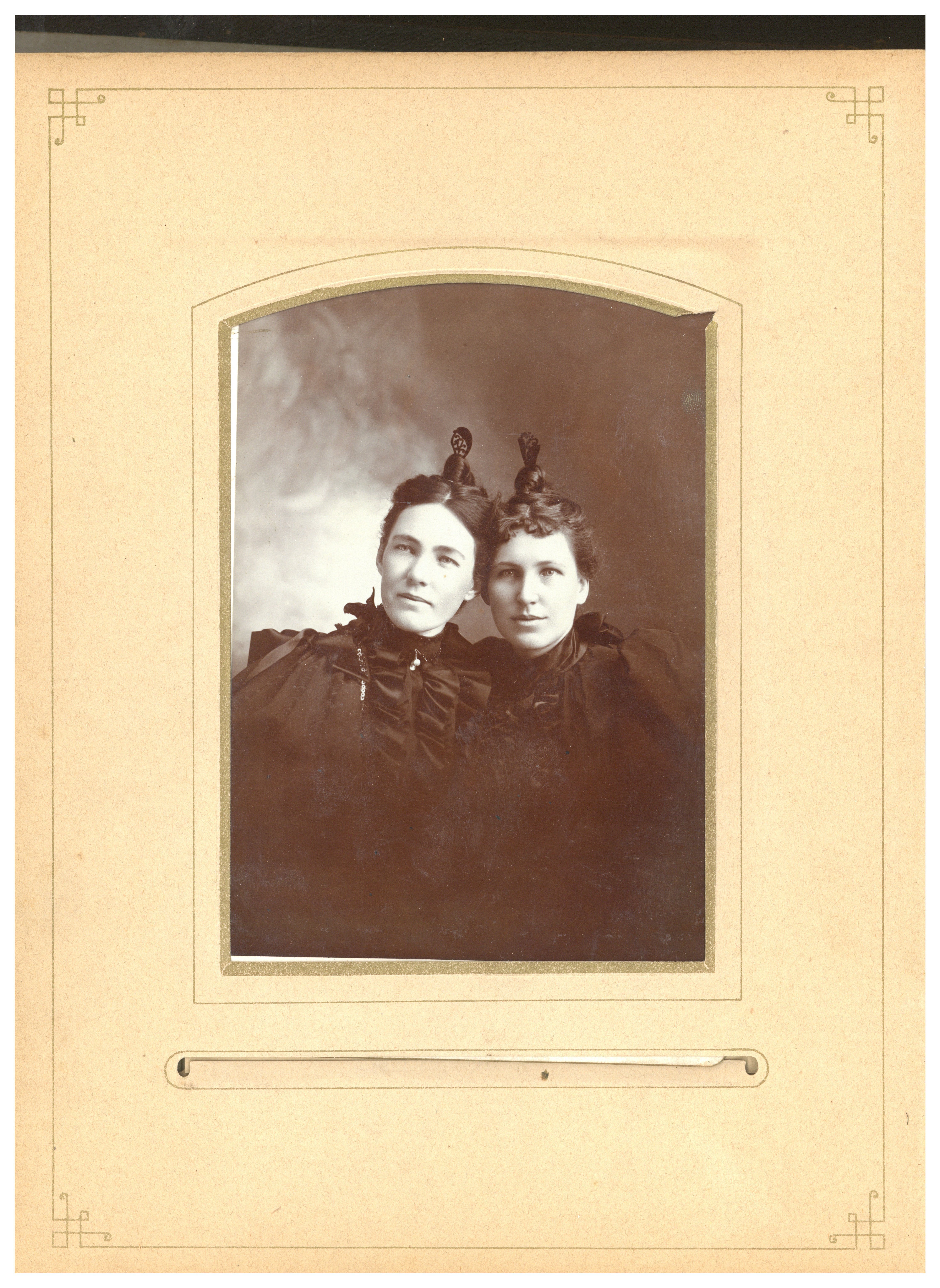 A black-and-white photograph of two women with leaf-shaped hair decorations.