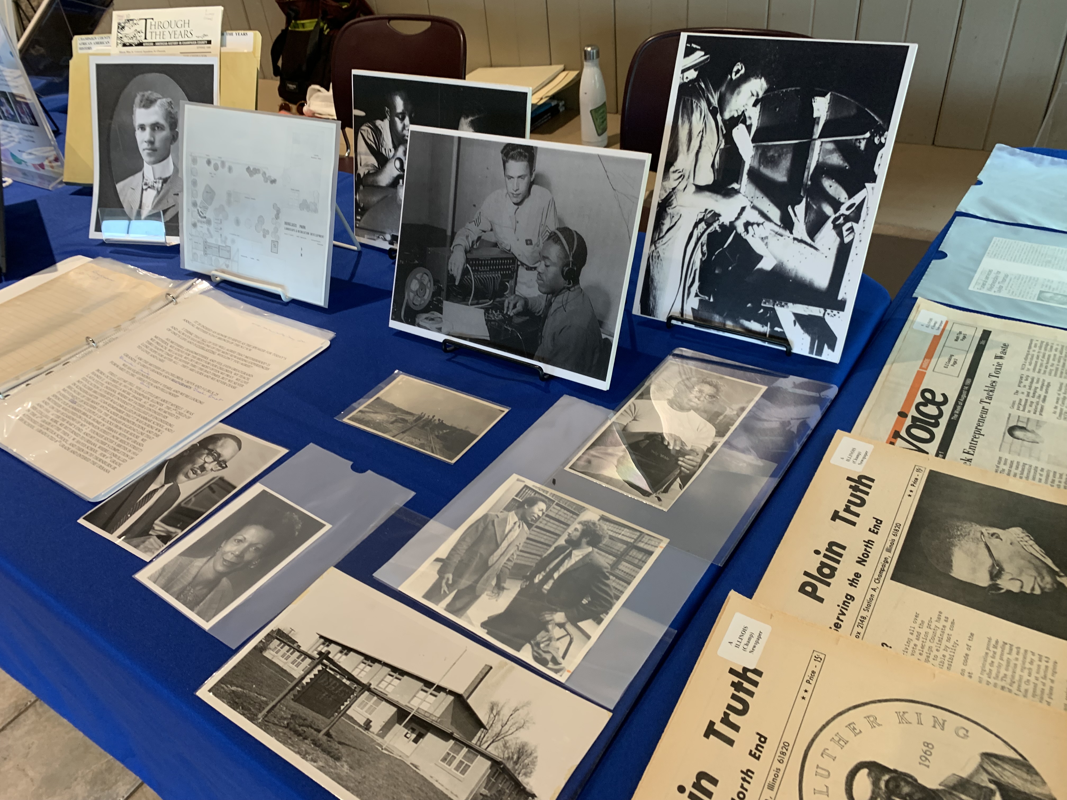 Photograph of archival material spread out on a table. There are photographs, documents, and newspapers.