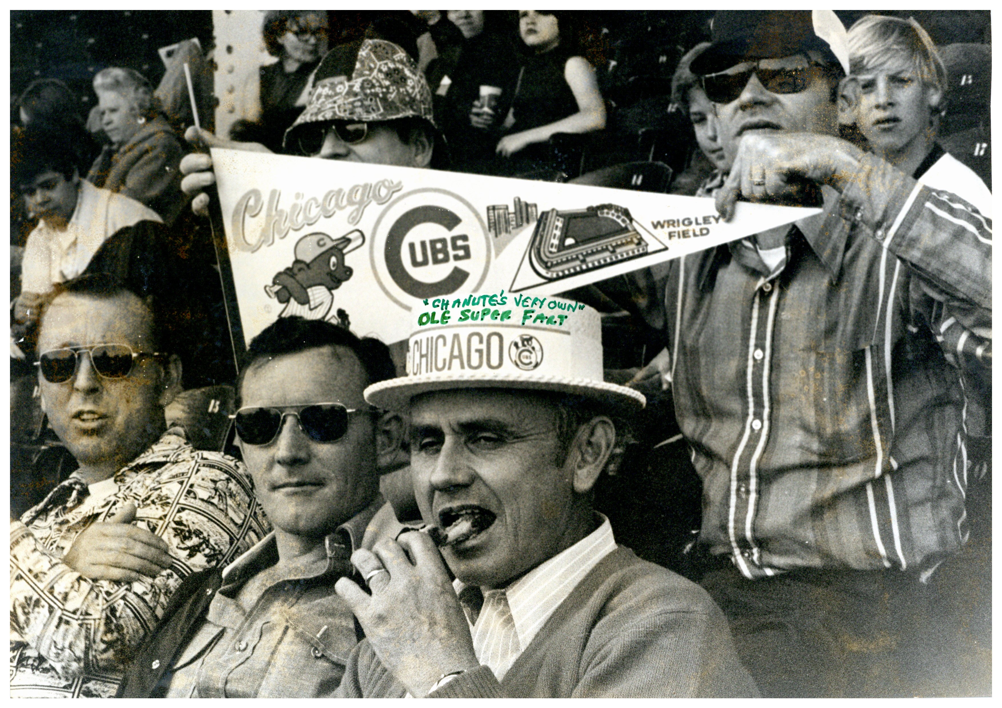 A group photo of Chanute "Ole-Fart" members at a cubs game. One is holding a pennant.