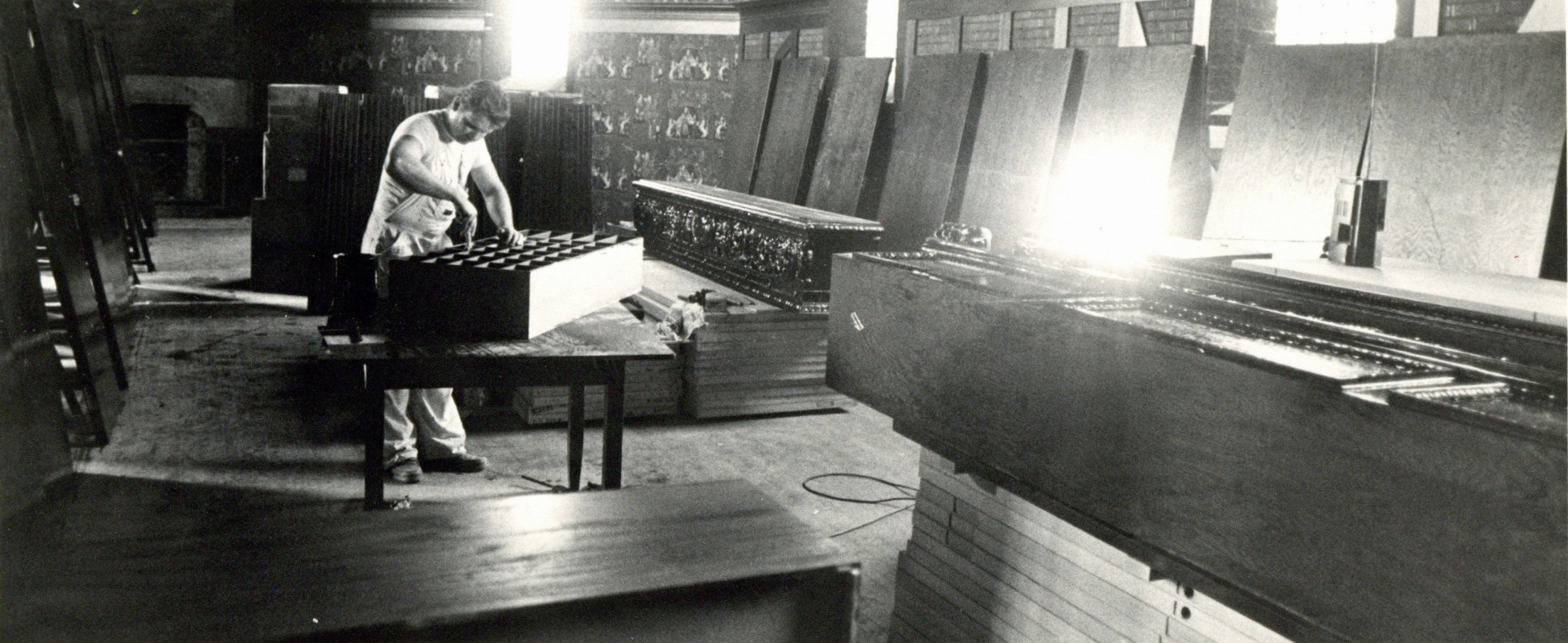 Black and white photograph of the interior of the hotel during renovations in the 1970s. A ban is standing over a table working, large slats of wood are leaning around the room.