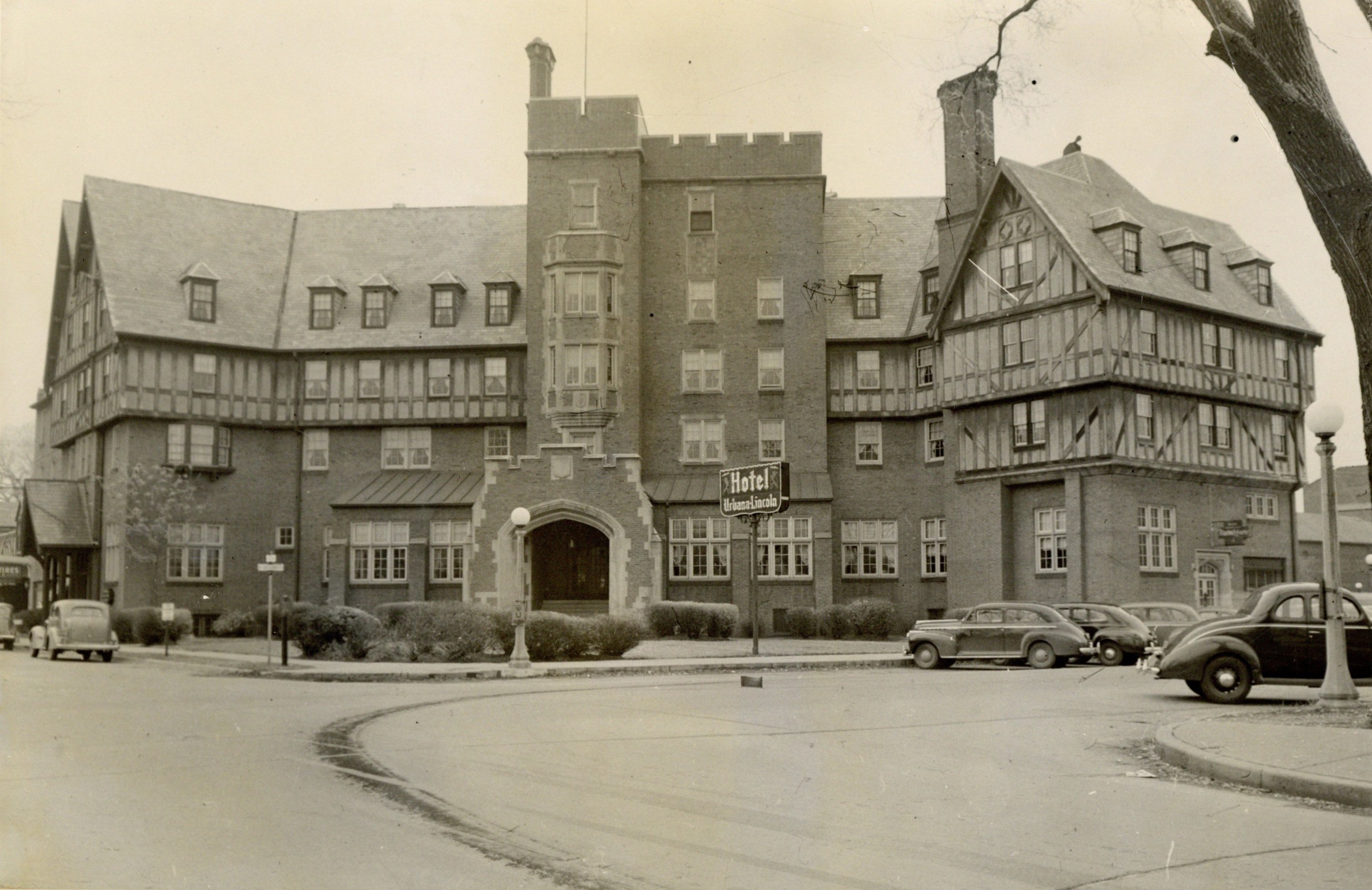 Black and white photograph of the Urbana Lincoln Hotel taken in 1941. The Tudor decorative elements are visible. Cars are parked in front of the hotel.