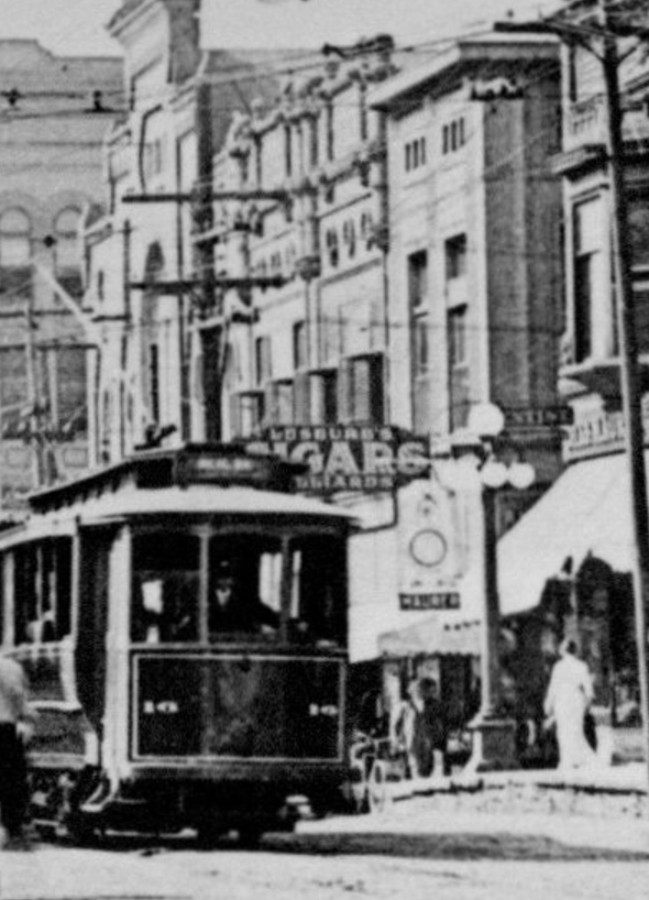 Close up crop of a street car and Leseure's Cigar shop.