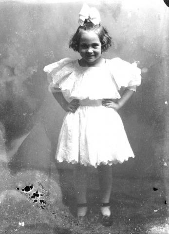 Young girl in party dress standing with her hands on her hips.
