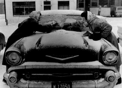 Two women clearing snow off a car's windshield, 1959 