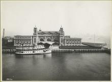 View of the front facade of the Immigration Station; a boat is docked in front.