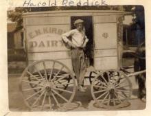 Horse-drawn dairy wagon, with young teenage male standing in wagon door 